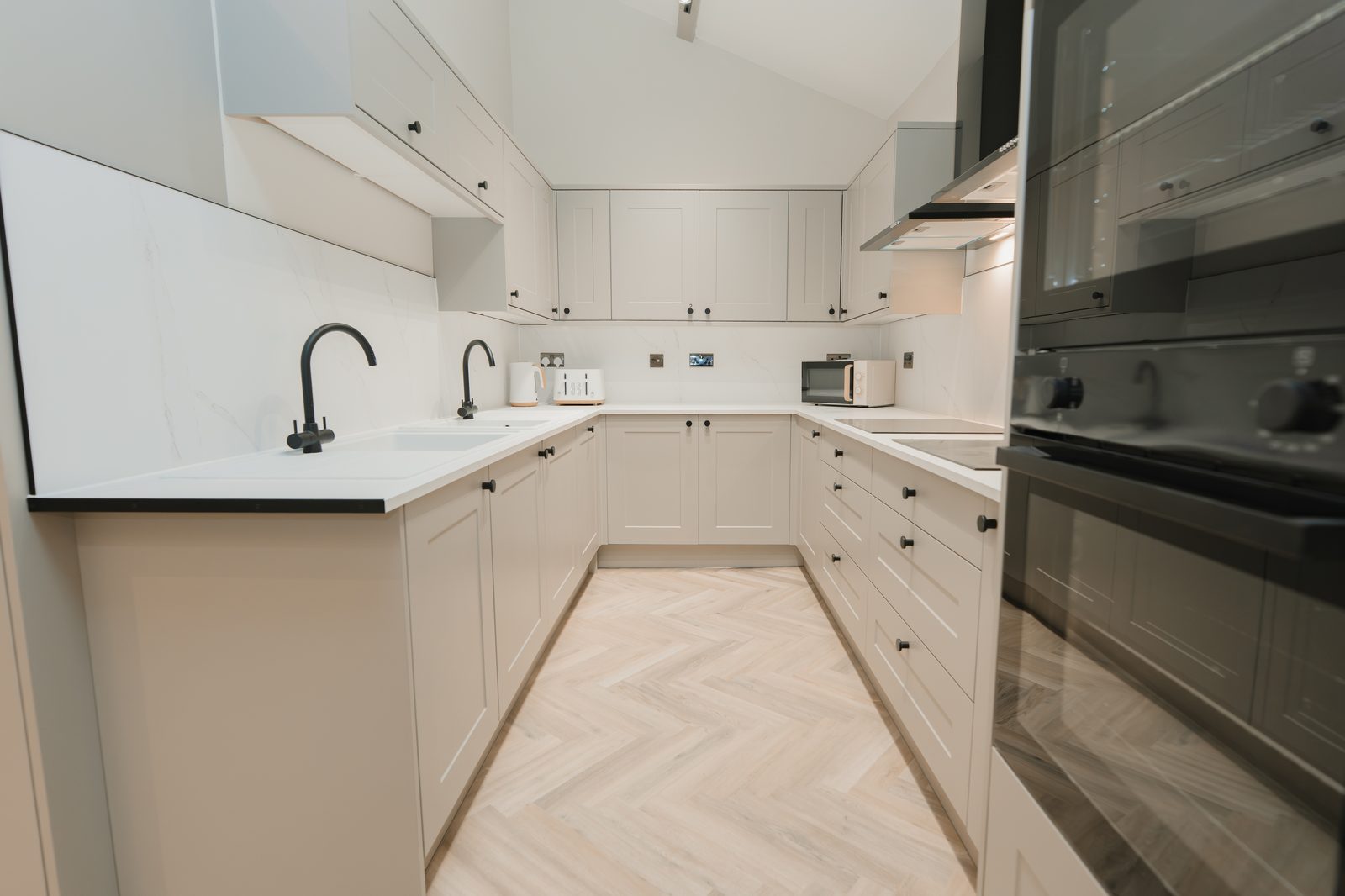 Communal kitchen with twin sinks, twin ovens and stone-effect worktops