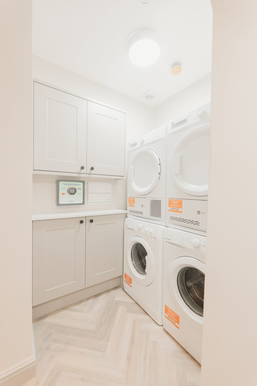 On-site laundry room with stacked machines and contactless card payment